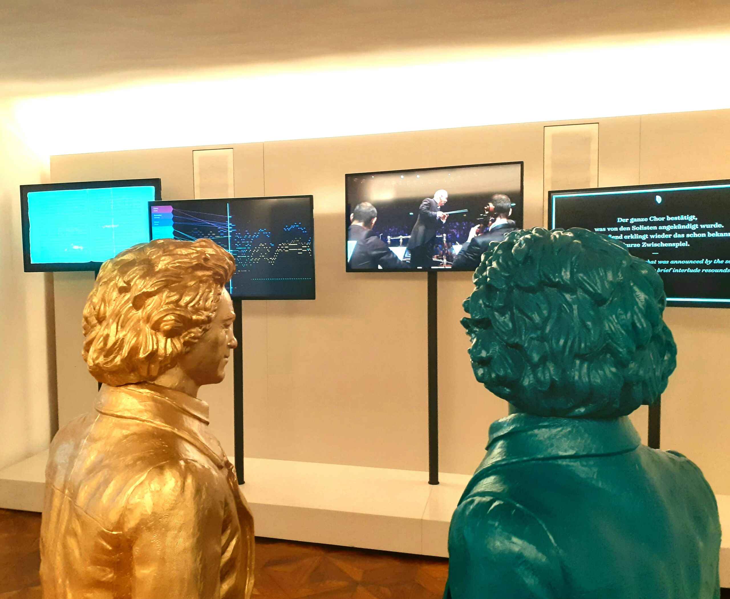 2 kleine Beethoven Skulpturen in türkis und gold stehen im Raum der Neunten, wo auf Screens die Neunte nachvollziehbar gemacht wird.